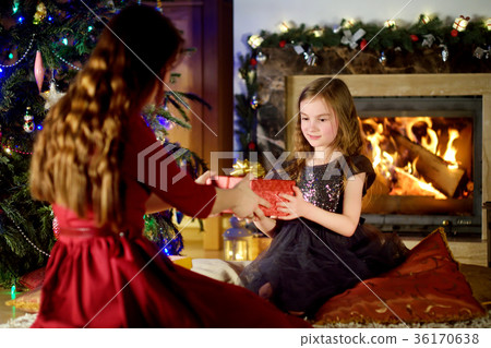 Happy little girl getting a Christmas gift from her parent 36170638