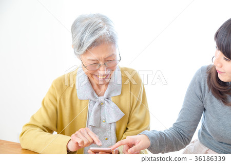 Grandmother teaching grandchild operation of mobile phone Grandmother and grandson young woman and old man Grandmother teaching grandchild operation of mobile phone Grandmother and grandson young woman and old man 36186339