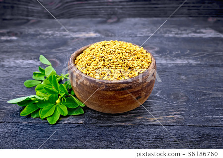 Fenugreek in clay bowl with green leaf on board Fenugreek in clay bowl with green leaf on board 36186760