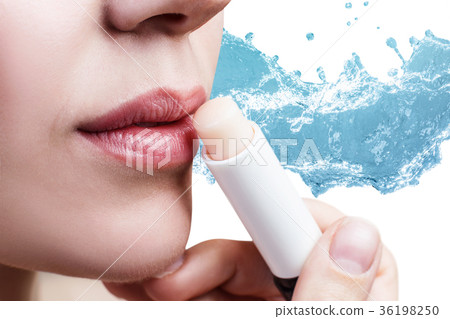 Woman applying lipbalm over water splashes 36198250