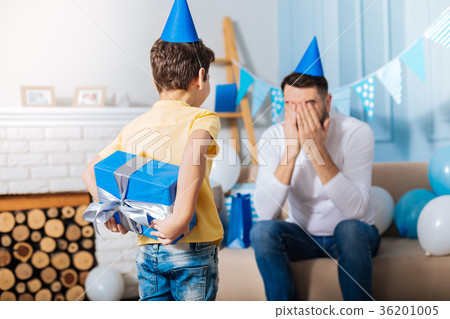 Little boy hiding fathers birthday gift behind his 36201005