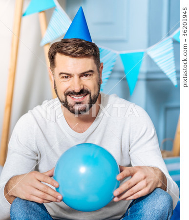 Pleasant man in party hat posing with balloon Pleasant man in party hat posing with balloon 36201948