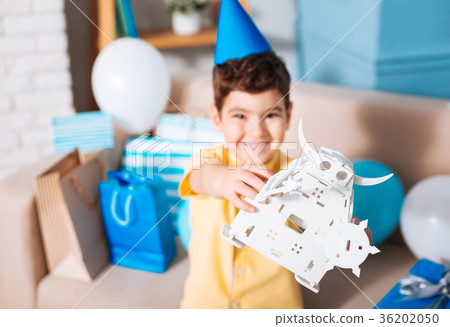 Smiling birthday boy showing his white toy robot Smiling birthday boy showing his white toy robot 36202050