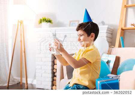 Upbeat little boy examining his birthday robot toy Upbeat little boy examining his birthday robot toy 36202052