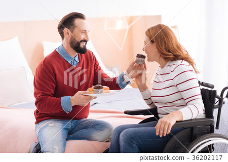 Alert man giving cookies to a paralyzed woman 36202117