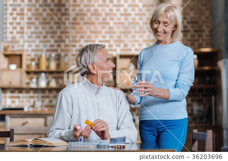 Laughing aged woman giving her husband a glass of 36203696