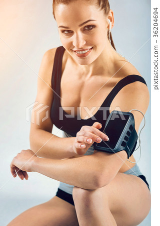 Charming female athlete sitting on floor and using 36204694