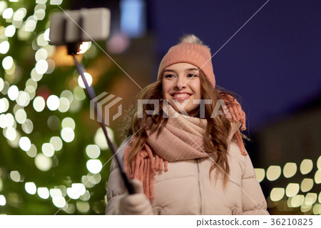 young woman taking selfie over christmas tree 36210825