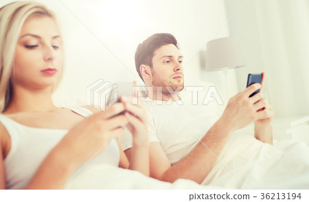 couple with smartphones in bed couple with smartphones in bed 36213194