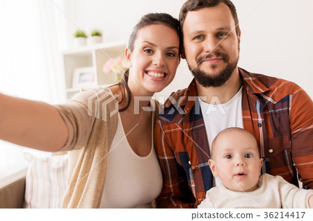 mother and father with baby taking selfie at home 36214417