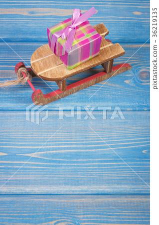 Wooden sled and wrapped gift with ribbons 36219135