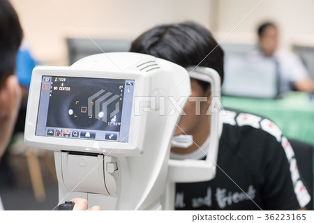 Woman looking at refractometer eye test machine 36223165