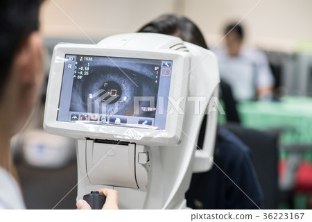 Woman looking at refractometer eye test machine Woman looking at refractometer eye test machine 36223167