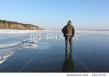 Man walking along the thin ice of a frozen river Man walking along the thin ice of a frozen river 36224703