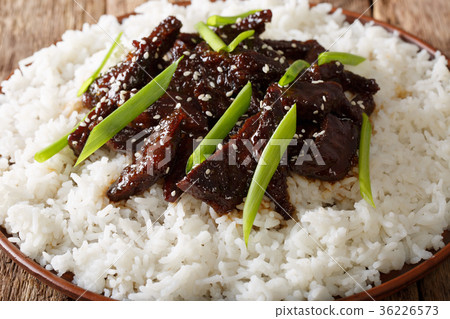 Mongolian beef with sauce and garnish of rice 36226573