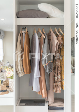 wooden wardrobe with clothes hanging on rail 36233831