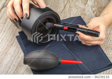 Photographer cleans the lens of the lens from dust Photographer cleans the lens of the lens from dust 36239110