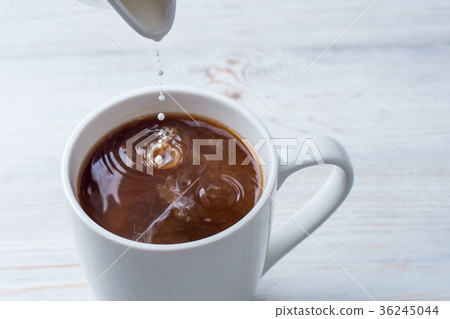 Adding milk to a cup of coffee Adding milk to a cup of coffee 36245044