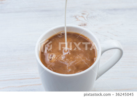 Adding milk to a cup of coffee Adding milk to a cup of coffee 36245045