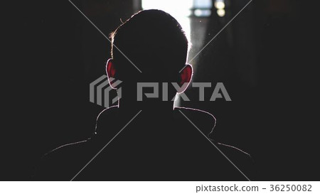 Silhouette of man standing by large window looking 36250082
