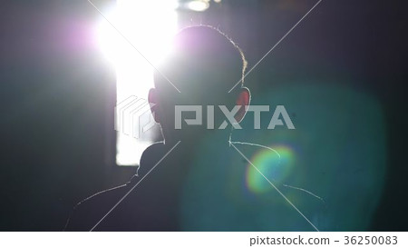 Silhouette of man standing by large window looking 36250083