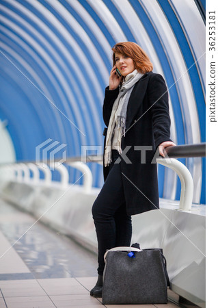Image of brunette in black coat talking on phone 36253181