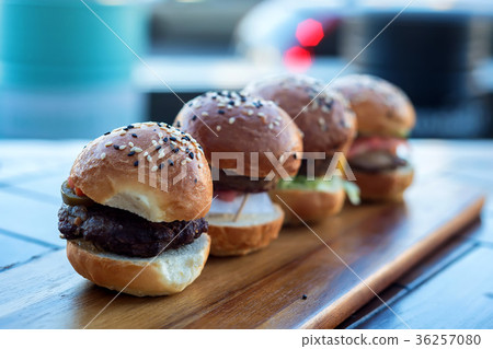 Four burgers on wooden board in restaurant 36257080