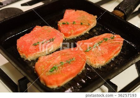 Four salmon steaks and herbs in frying pan 36257193