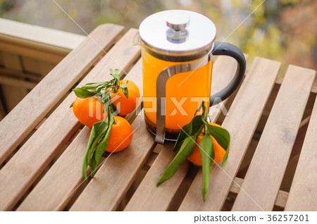 Glass teapot with orange drink and tangerines Glass teapot with orange drink and tangerines 36257201