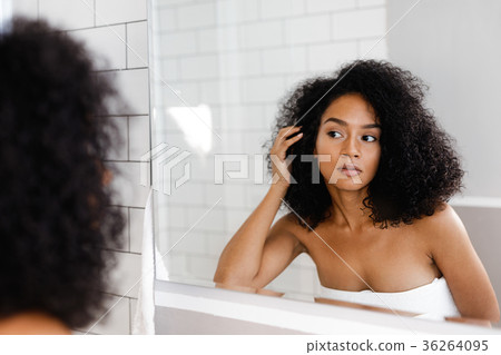Young woman standing in bathroom, holding hair 36264095