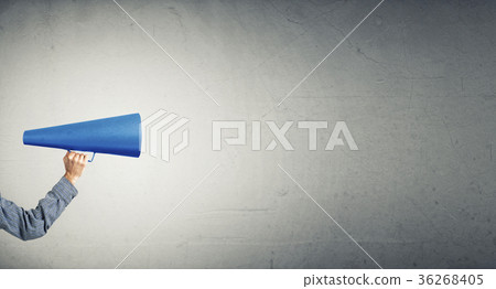 Hand of man holding paper trumpet against concrete background 36268405