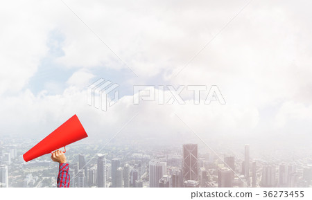 Hand of woman holding red paper trumpet against cityscape background Hand of woman holding red paper trumpet against cityscape background 36273455