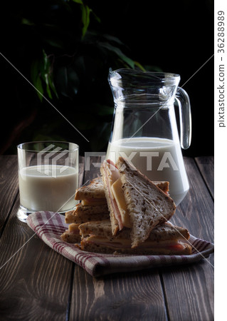 Sandwich and pitcher of milk. Dark tone. 36288989