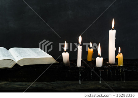 Bible and candle on an old wooden burnt table 36298336