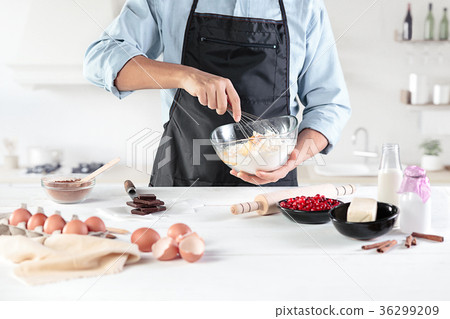 A cook with eggs on a rustic kitchen against the A cook with eggs on a rustic kitchen against the 36299209