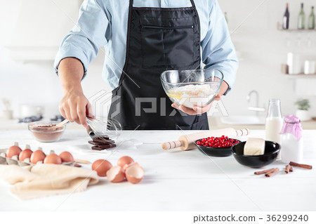 A cook with eggs on a rustic kitchen against the A cook with eggs on a rustic kitchen against the 36299240