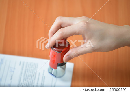 Female hand hold rubber stamps over documents and Female hand hold rubber stamps over documents and 36300591