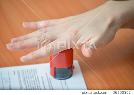 Female hand pushing rubber stamps on document at Female hand pushing rubber stamps on document at 36300592