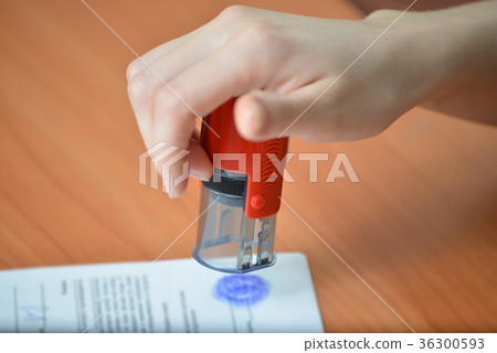 Female hand hold rubber stamps over documents and Female hand hold rubber stamps over documents and 36300593