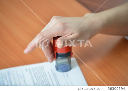 Female hand pushing rubber stamps on document at Female hand pushing rubber stamps on document at 36300594