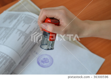 Female hand hold rubber stamps over documents and Female hand hold rubber stamps over documents and 36300596