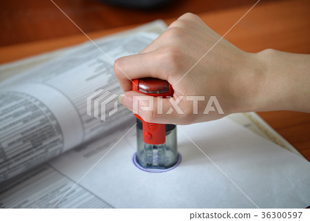 Female hand pushing rubber stamps on document at Female hand pushing rubber stamps on document at 36300597