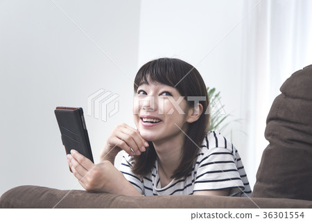 A young lady who operates a smartphone lying on the sofa 36301554