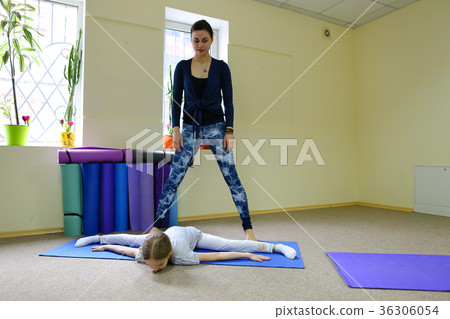 Little girl sits on twine and trainer helps child. 36306054