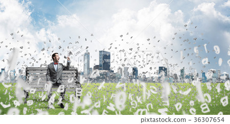 Businessman in summer park on bench announcing something in loudspeaker and symbols fly around Businessman in summer park on bench announcing something in loudspeaker and symbols fly around 36307654