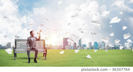 Businessman in summer park announcing something in loudspeaker and paper planes flying around Businessman in summer park announcing something in loudspeaker and paper planes flying around 36307764