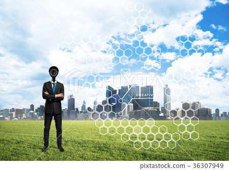 Camera headed man standing on green grass against modern cityscape 36307949