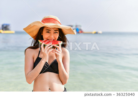 Beautiful girl wearing swimsuit eating watermelon beach. 36325040
