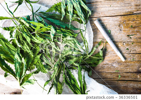 Dried marijuana leafs and a joint on a table 36336501