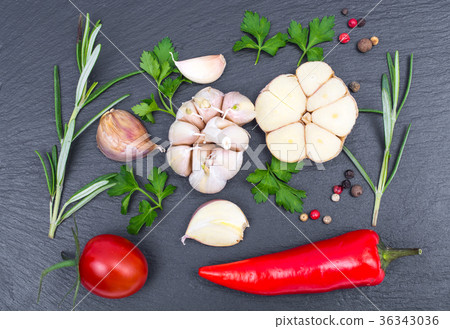Garlic, chili, spices and herbs on black stone 36343036